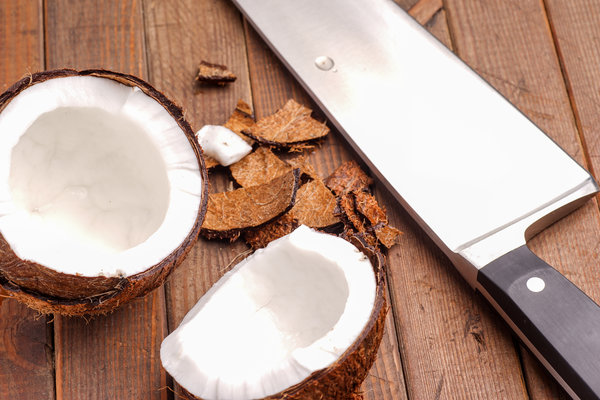 Coconut, broken and open ready for eating on wood board https://cleanfoodcrush.com/coconut-oil-benefits-part1