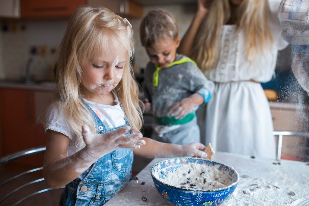 Little girl and boy helping mom to prepare the meal