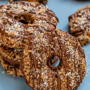A stack of samoa cookies with one facing front and leaning on the stack.