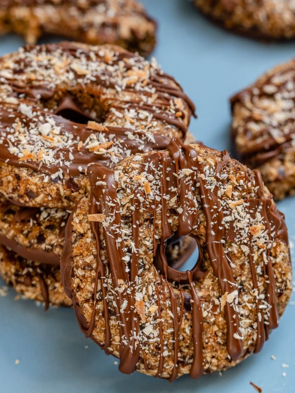 A stack of samoa cookies with one facing front and leaning on the stack.