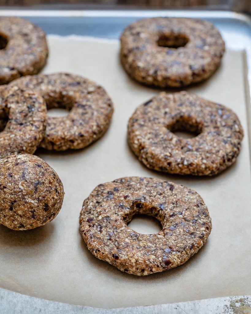 Dates and coconut flakes rolled into a ball and then flattened into cookie rings on a piece of parchment paper.