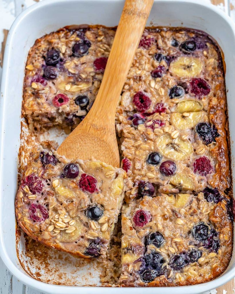 Baked protein oats cut into six pieces and being scooped out by a wooden spatula.