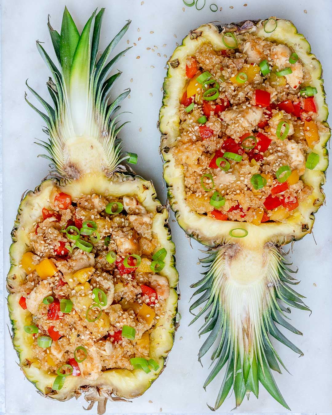 Two pineapple halves stuffed with pineapple chicken and quinoa.