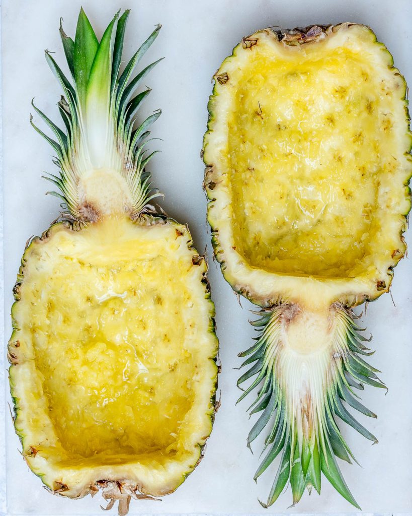 Two hollowed out pineapple halves to make pineapple chicken bowls.