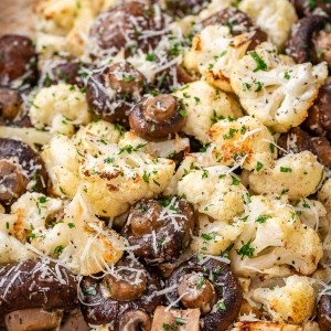 A tray of roasted cauliflower and mushrooms sprinkled with parmesan cheese and parsley.