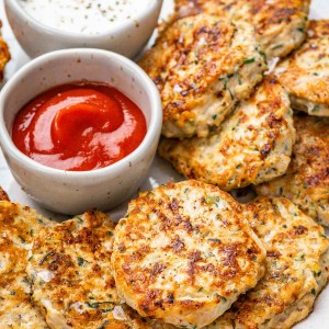 Chicken zucchini fritters next to a ramekin of ketsup.