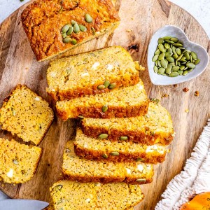 High protein pumpkin lentil bread sliced on a cutting board near a heart shaped dish of lentils.