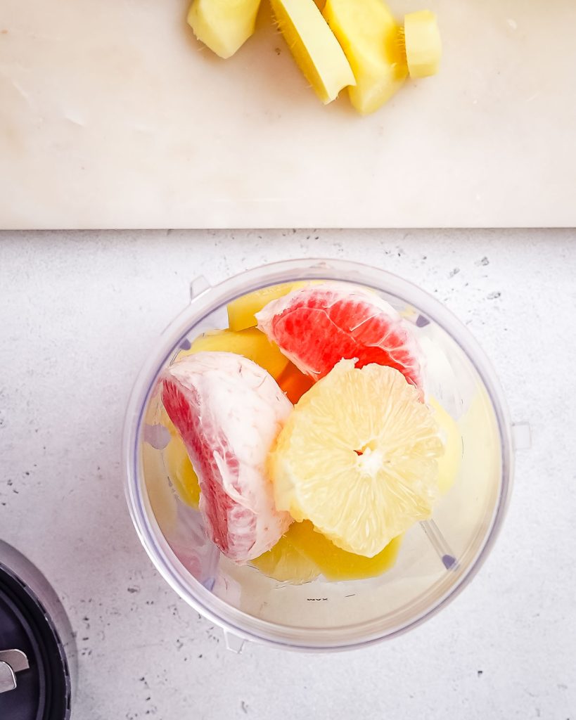 Orange, grapefruit, and ginger segments in a blender cup.
