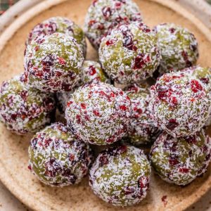 Christmas energy balls stacked up on a tan plate.