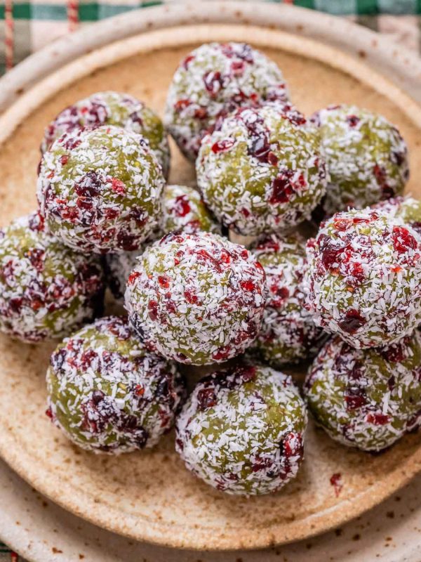 Christmas energy balls stacked up on a tan plate.
