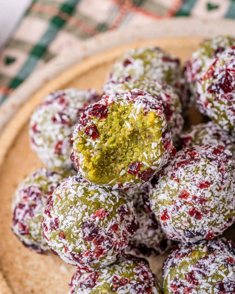 A stack of christmas energy balls with one ball having a bite taken out of it showing the green inside.