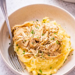 Image of french onion chicken shredded and on top of mashed potatoes.