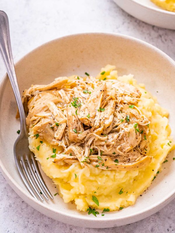 Image of french onion chicken shredded and on top of mashed potatoes.