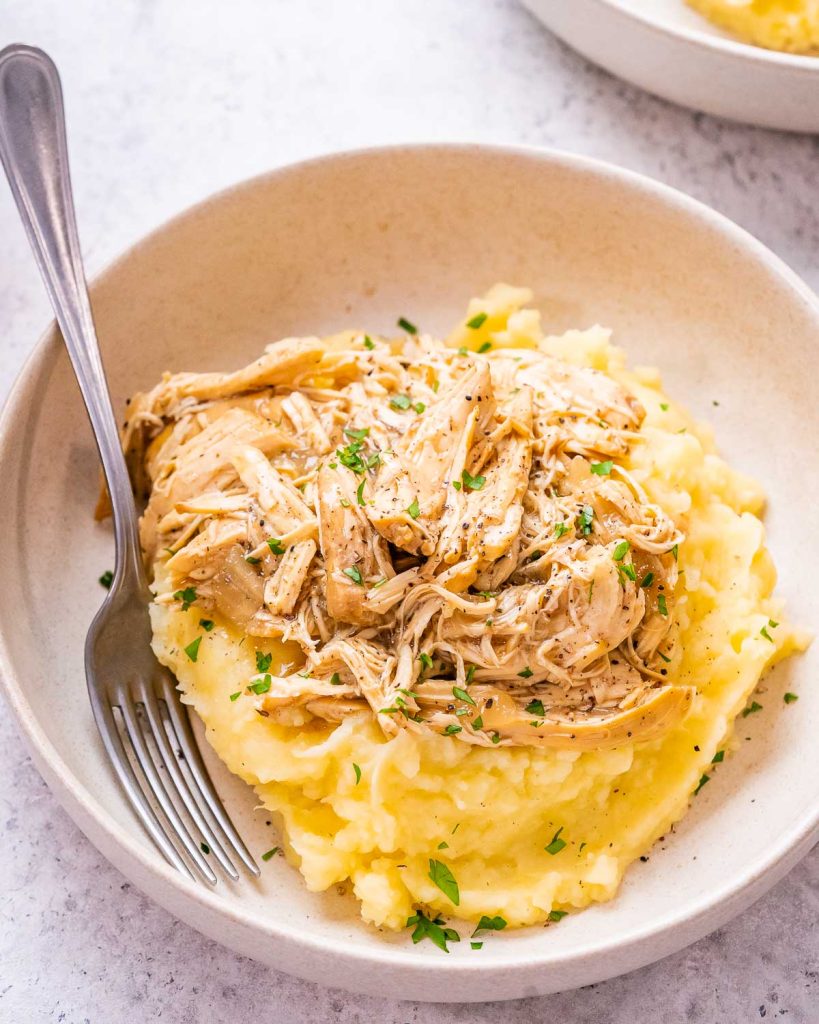 Image of french onion chicken shredded and on top of mashed potatoes.