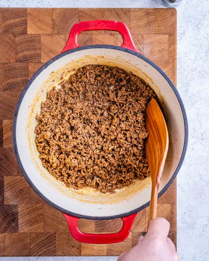 Browned ground beef in an enameled cast iron pot.