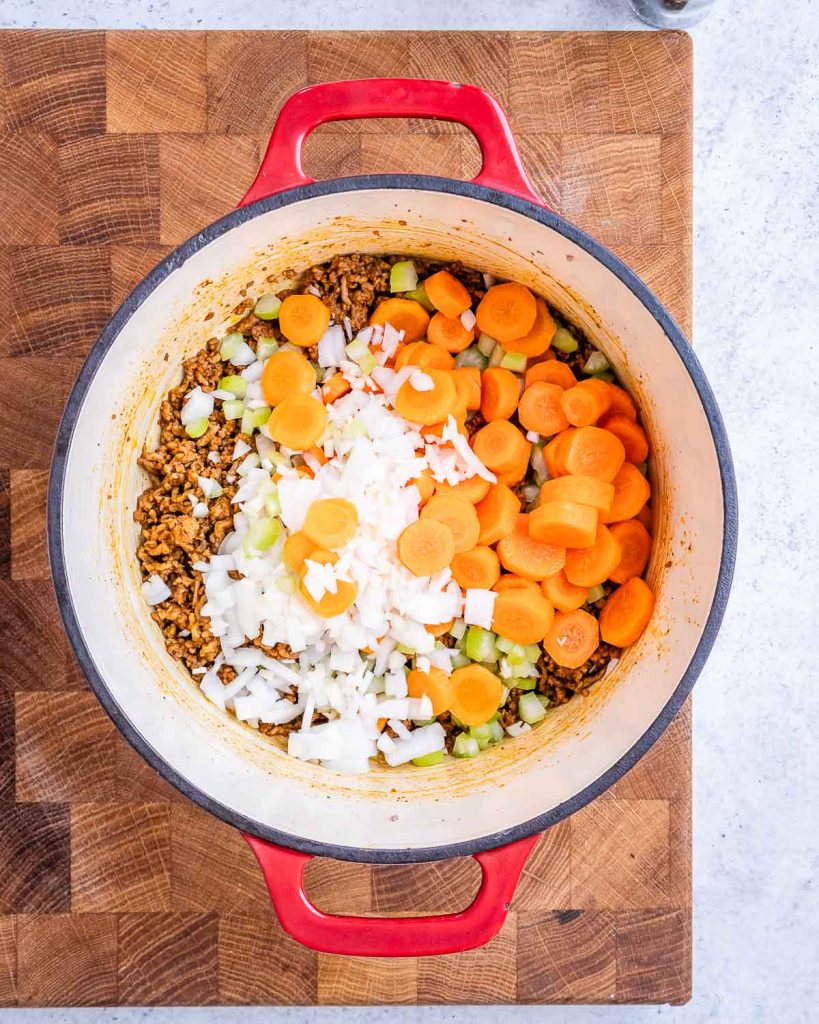 Onion, carrot, celery and garlic added to the cooked ground beef in a stock pot.