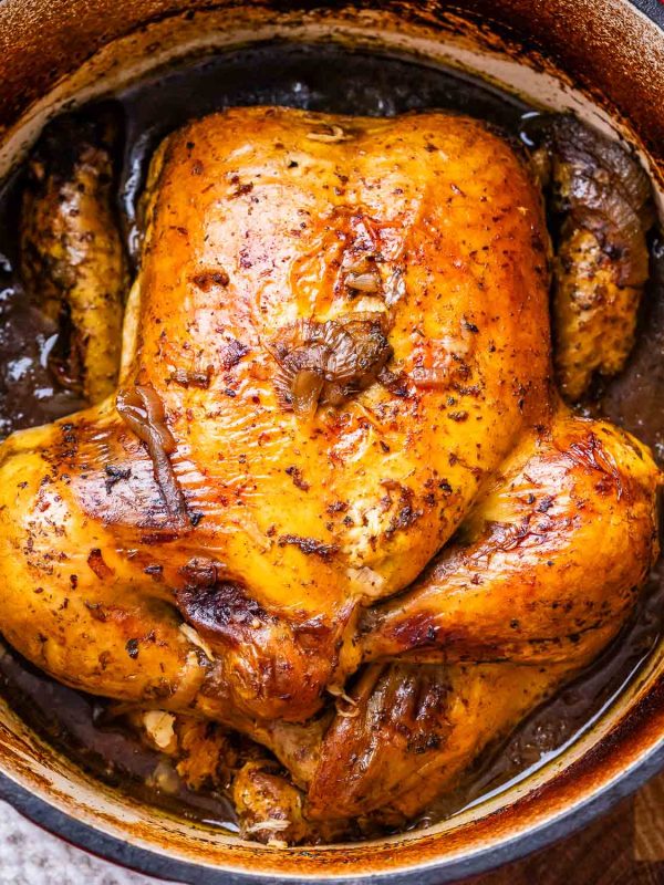 Image of a roasted balsamic chicken in a deep pan filled with brown liquid.