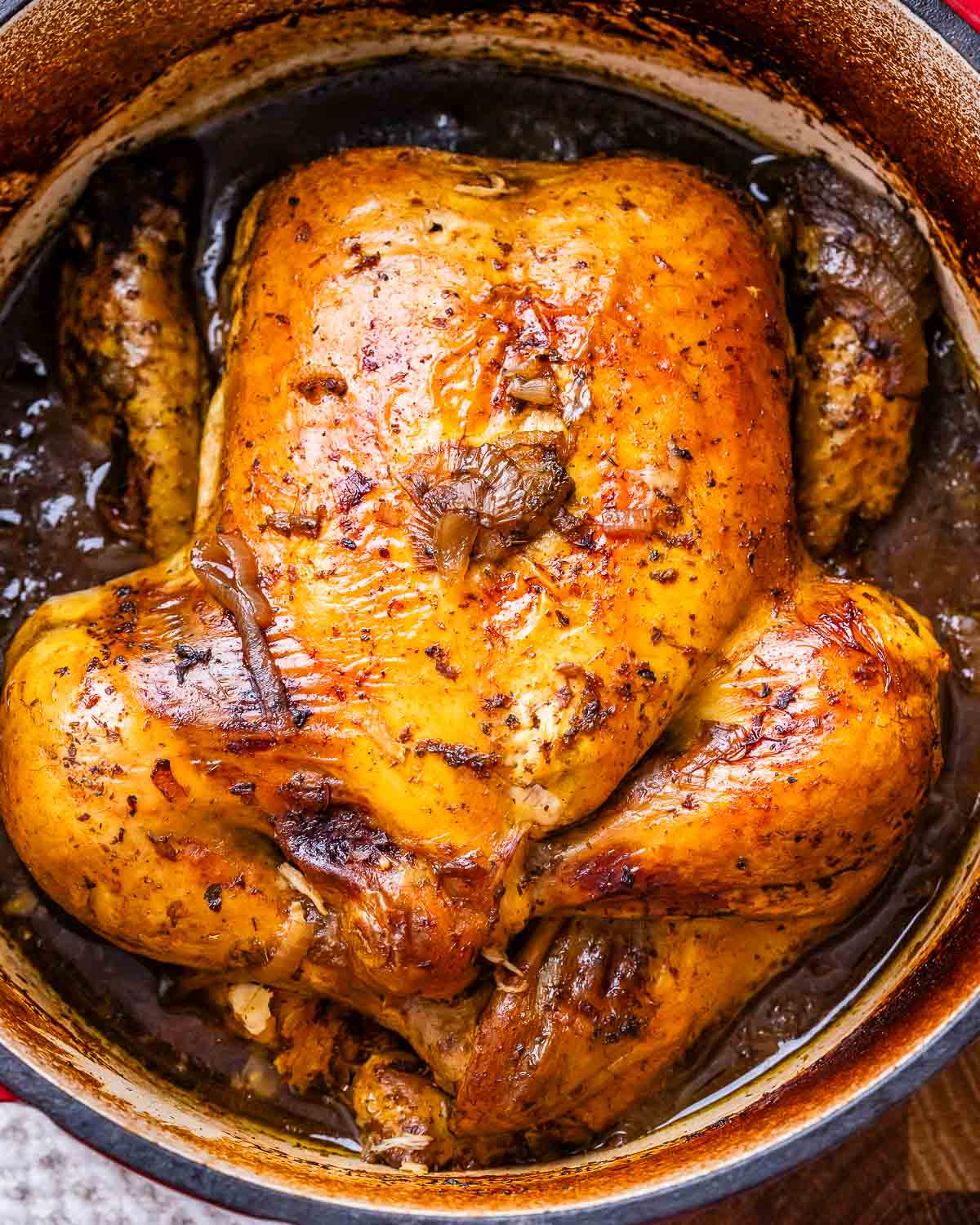 Image of a roasted balsamic chicken in a deep pan filled with brown liquid.