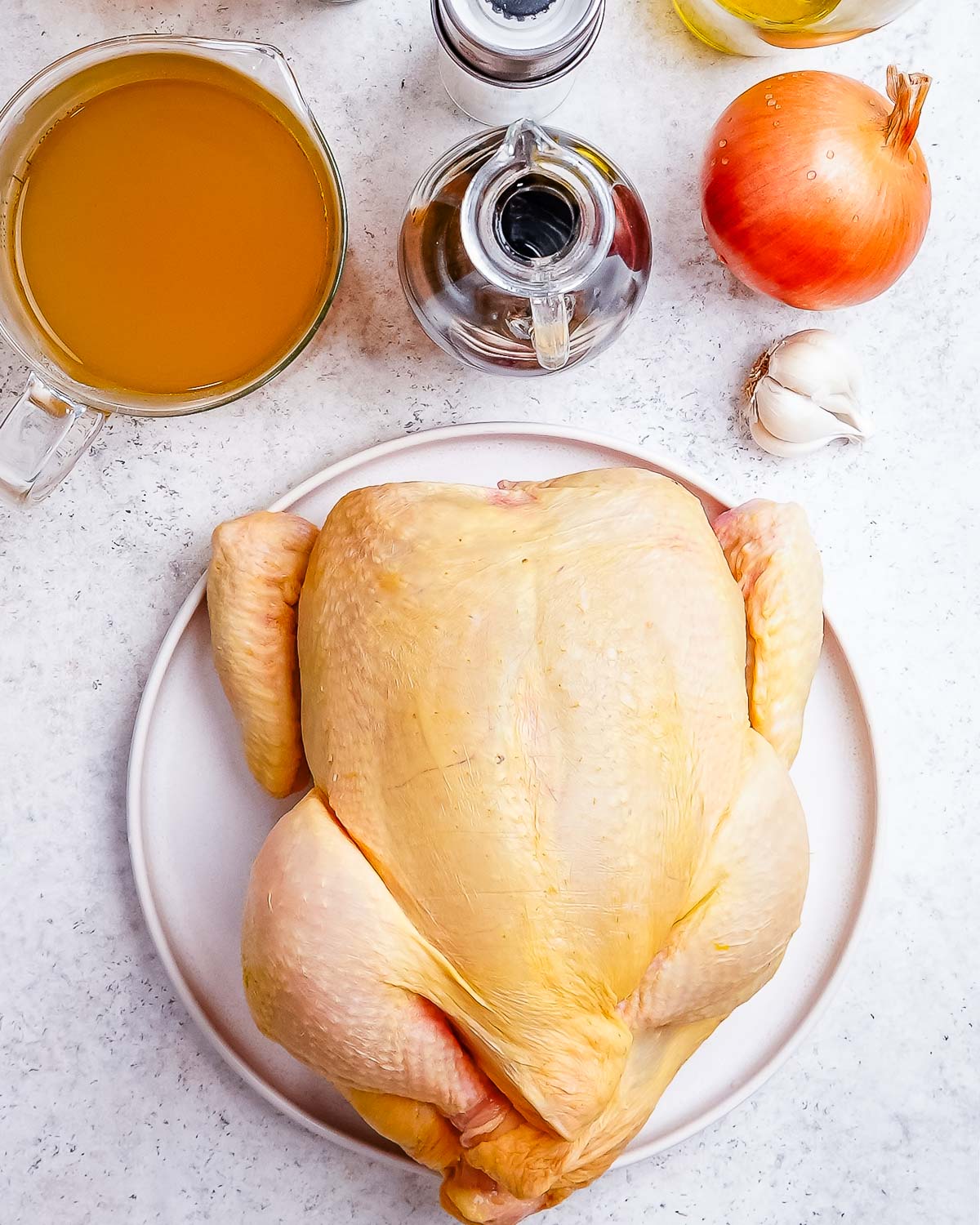 Ingredients to make balsamic chicken: chicken stock, balsamic vinegar, onion, garlic, and a whole chicken.