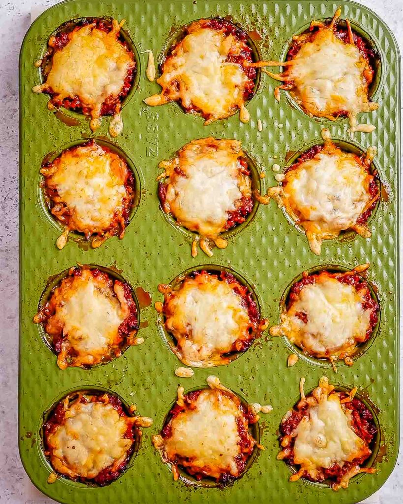 Fully baked cheesy zucchini lasagna bites in a green muffin tin.