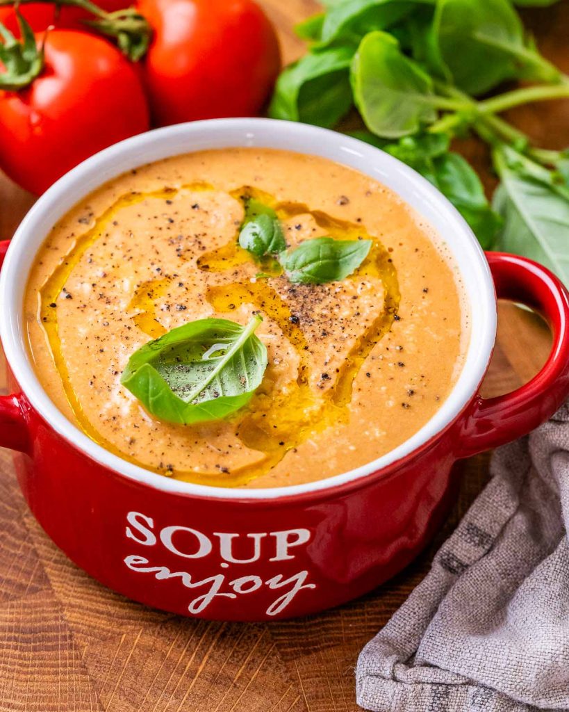 High-protein roasted tomato soup in a red bowl with a handle that says soup enjoy on the side in white letters.