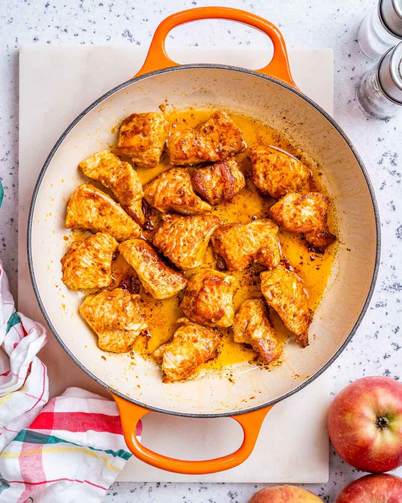 Browned diced turkey to make turkey stew in a Dutch oven with orange handles.