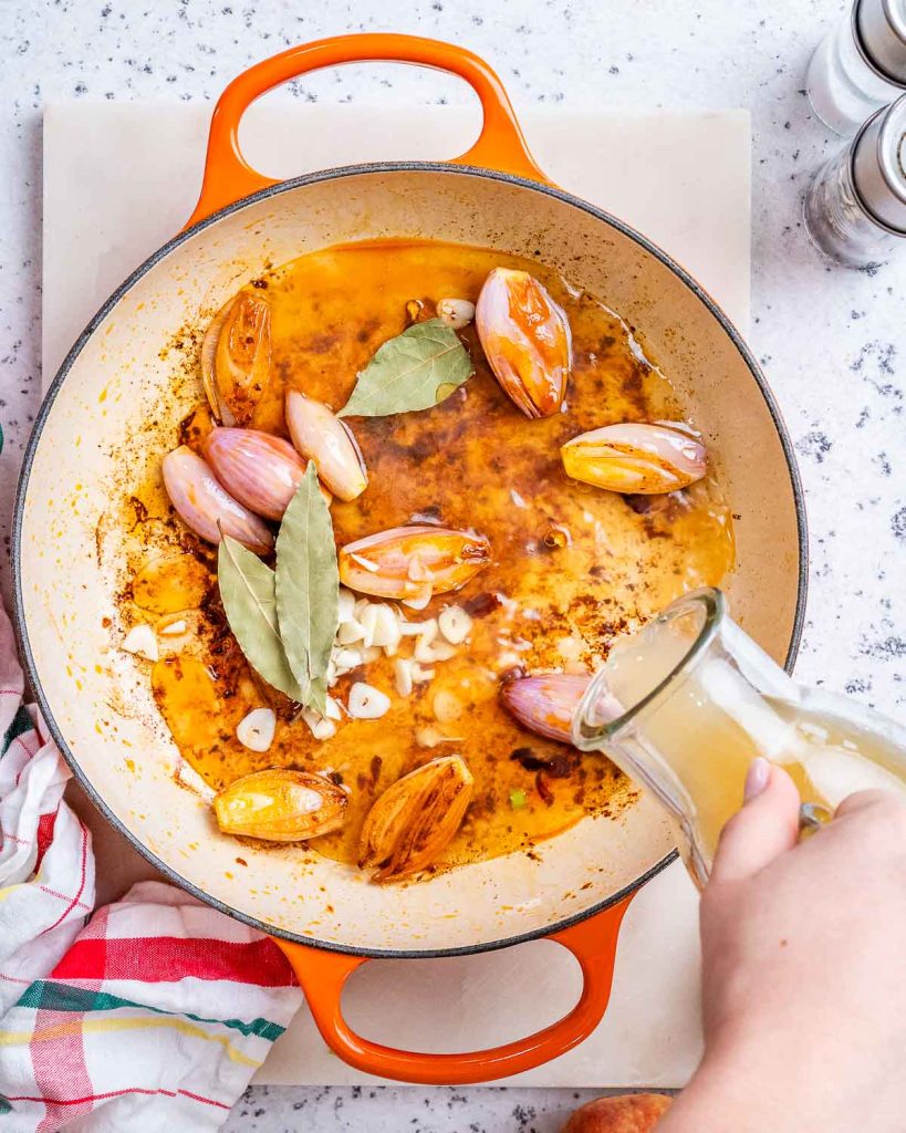 Whole shallots, apple cider and garlic added to pot to make turkey stew.