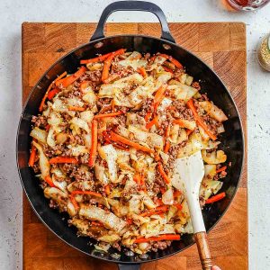 Ground beef and cabbage stir fry in a skillet.
