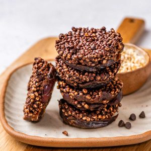 chewy and crunchy chocolate date quinoa bites stacked on a plate.