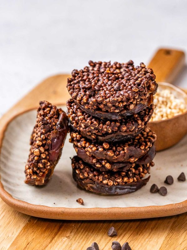 chewy and crunchy chocolate date quinoa bites stacked on a plate.