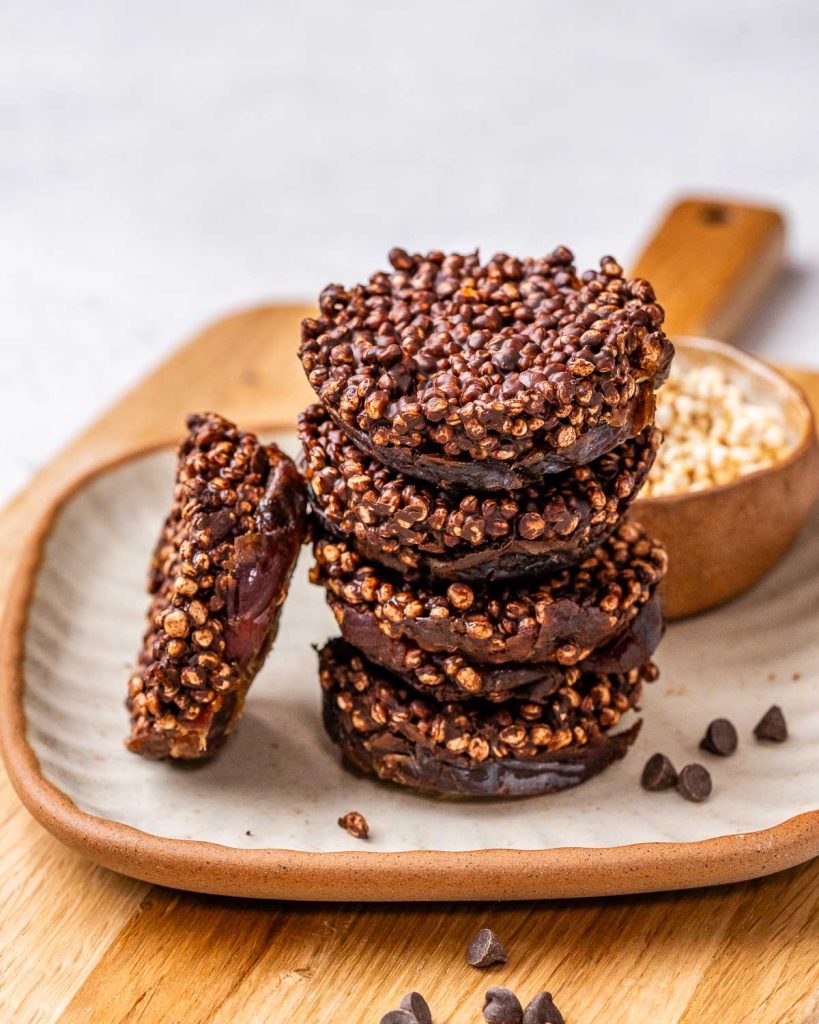 chewy and crunchy chocolate date quinoa bites stacked on a plate.