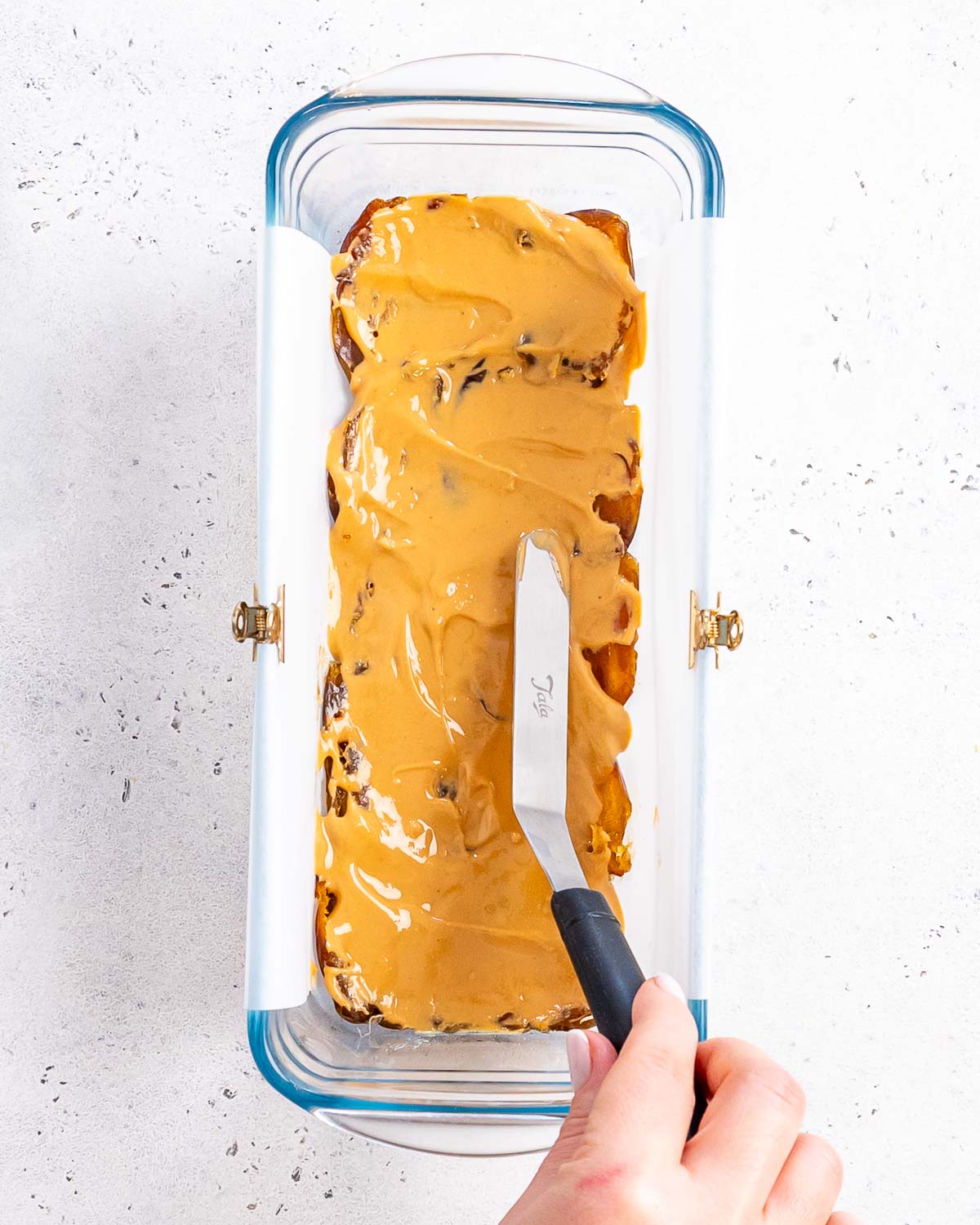 peanut butter being spread over the dates for healthy snickers with dates recipe.