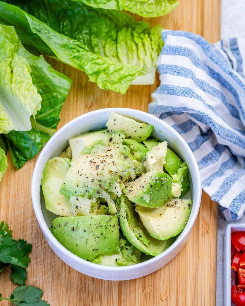avocado added to a bowl to make guacamole.