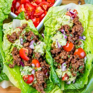 two ground beef lettuce wraps with tomatoes and guacamole.