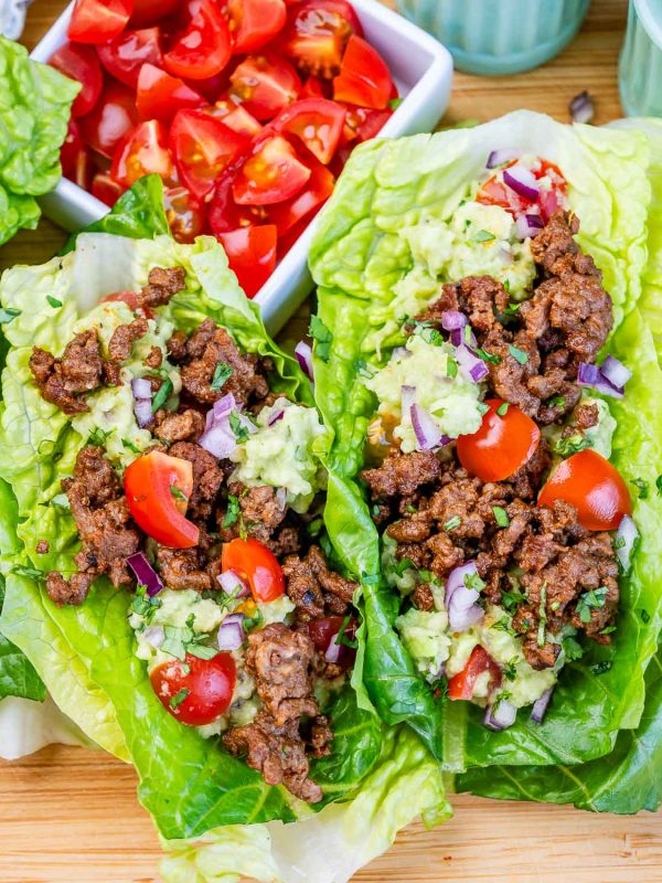 two ground beef lettuce wraps with tomatoes and guacamole.
