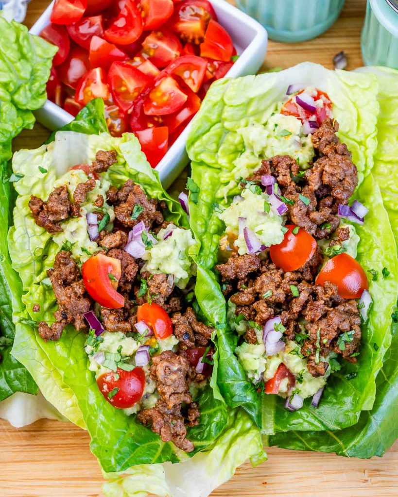 two ground beef lettuce wraps with tomatoes and guacamole.