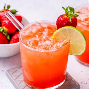 homemade electrolyte drink in a glass and garnished with a strawberry and lime.