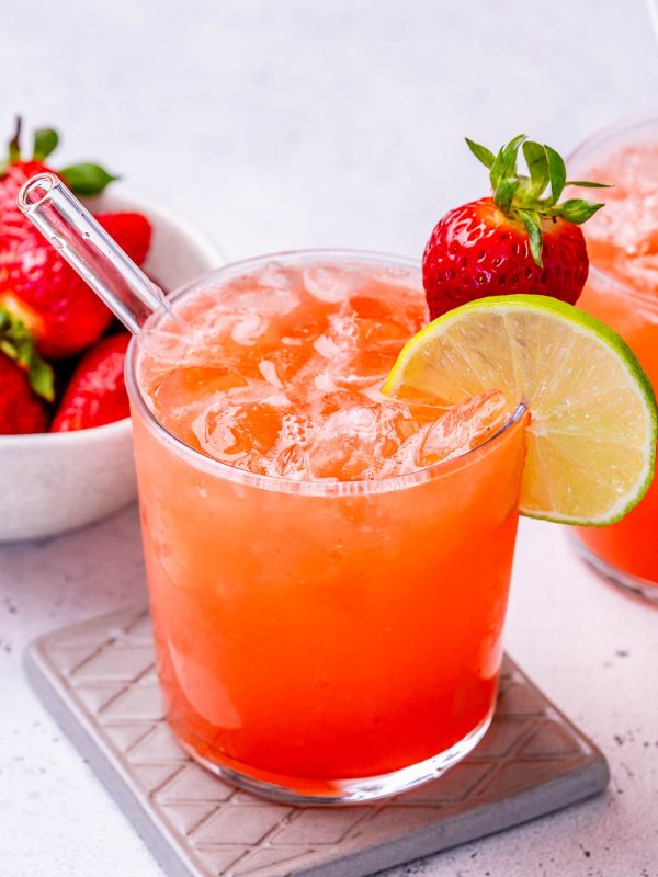 homemade electrolyte drink in a glass and garnished with a strawberry and lime.